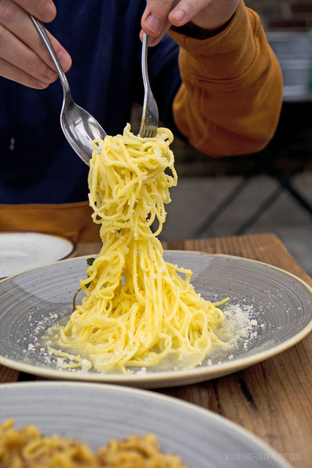 man picking up spaghetti with a fork and spoon dramatically