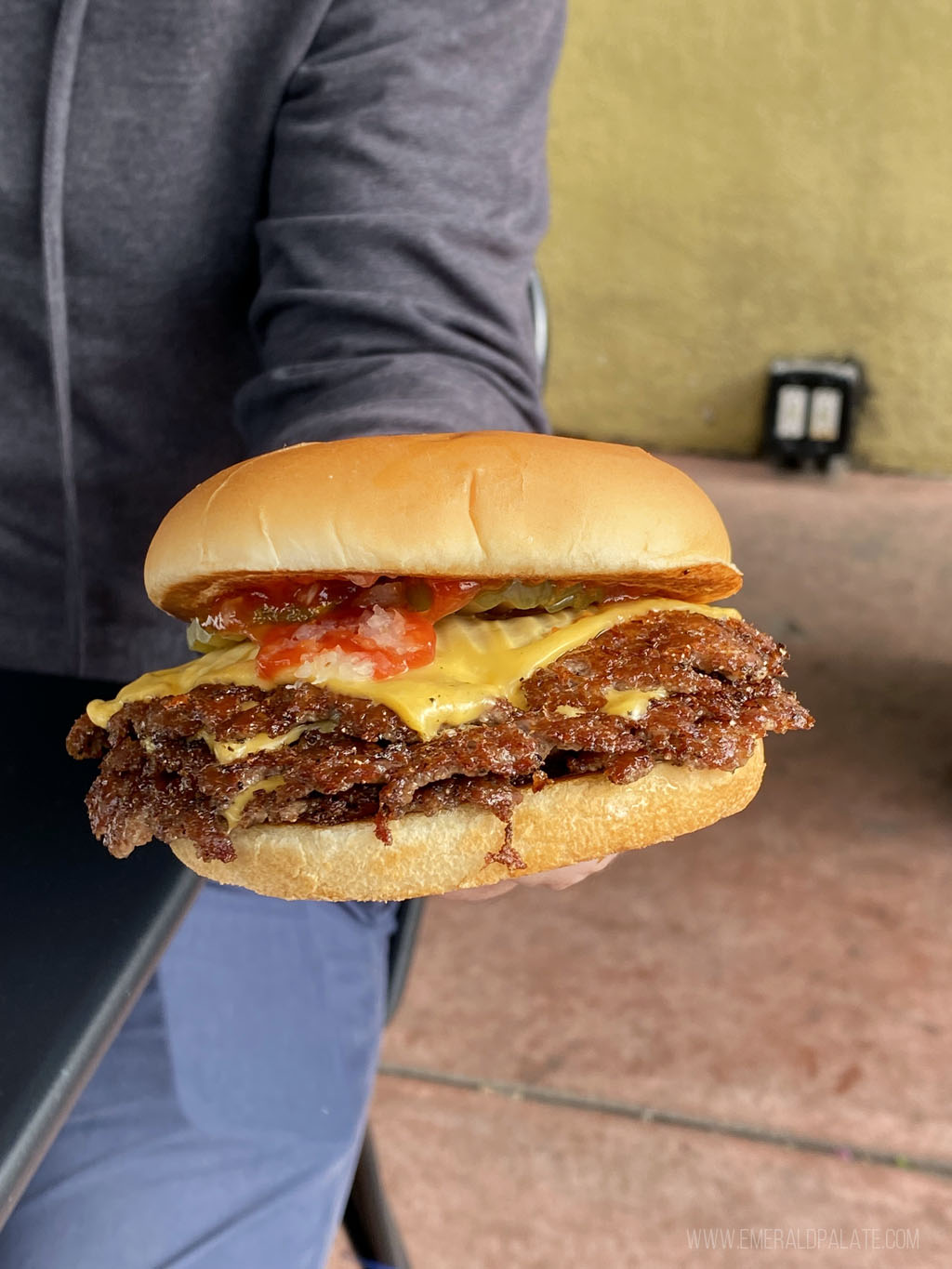person holding a triple stack cheeseburger from a burger joint in LA