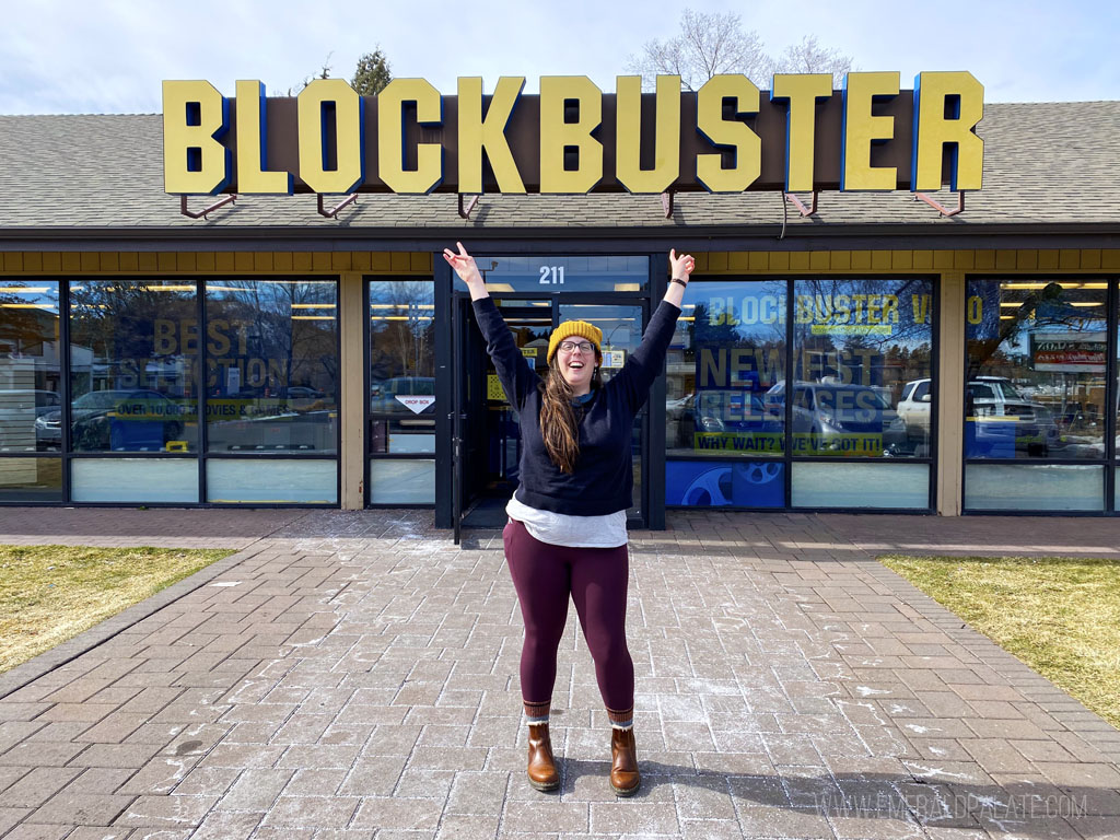 woman cheering in front of the last Blockbuster movie rental store in Bend, Oregon