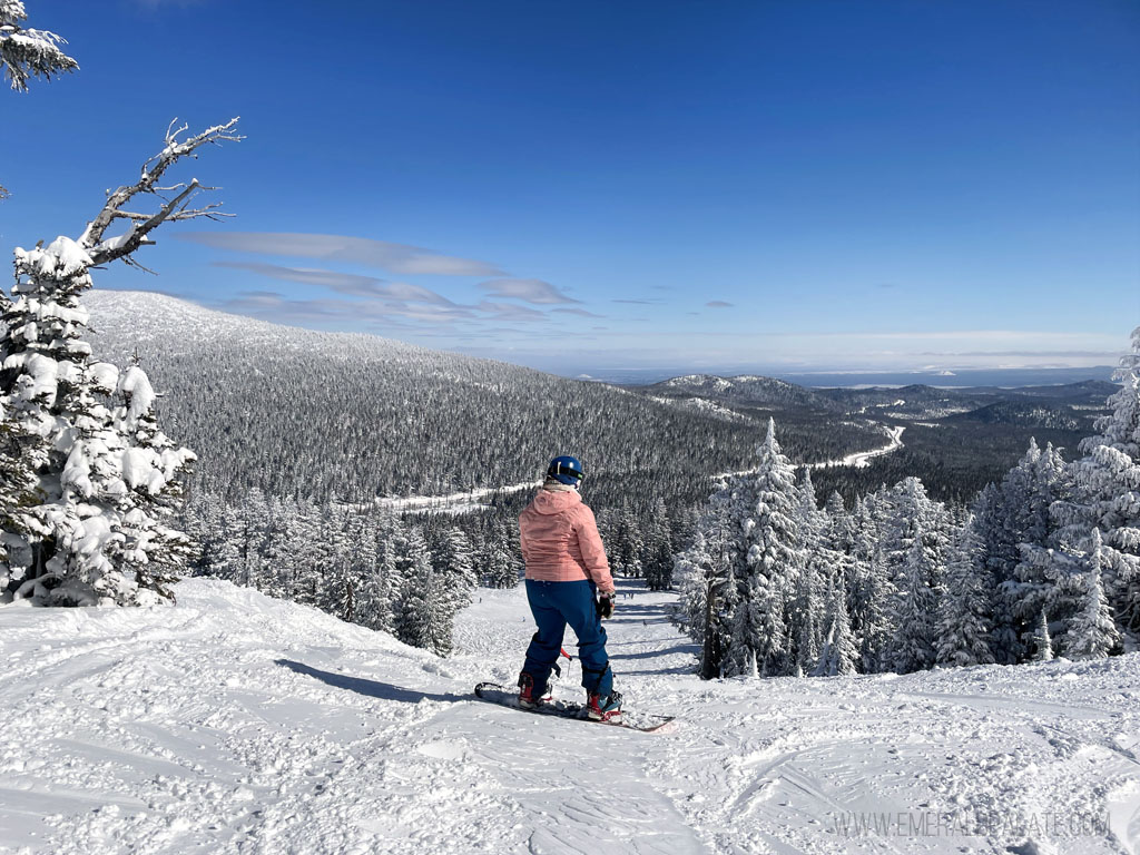 woman taking a break from snowboarding to look out at Mt. Bachelor, Oregon