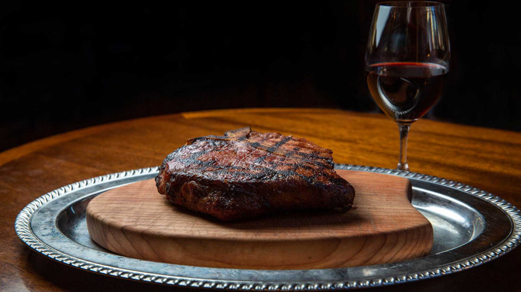 steak cut on a platter with wine