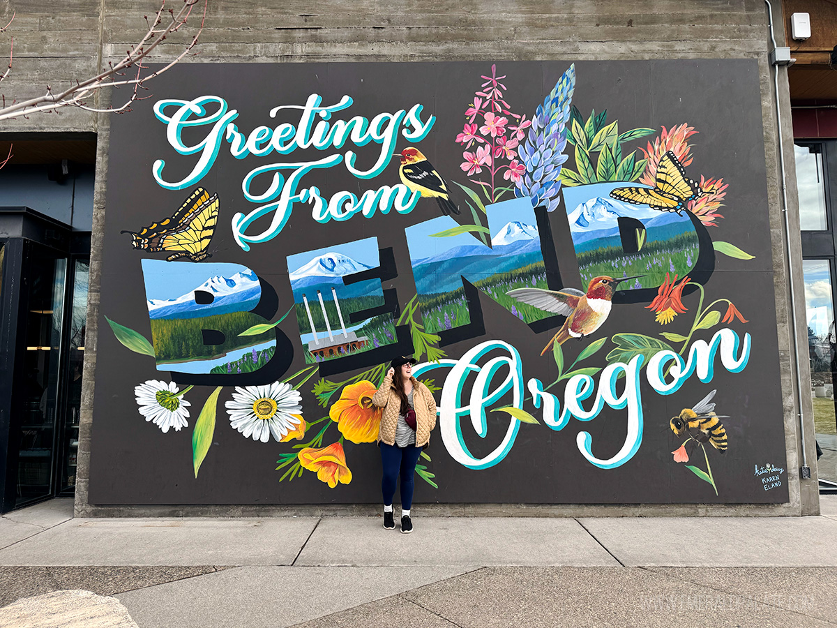 woman laughing in front of a Bend Oregon mural