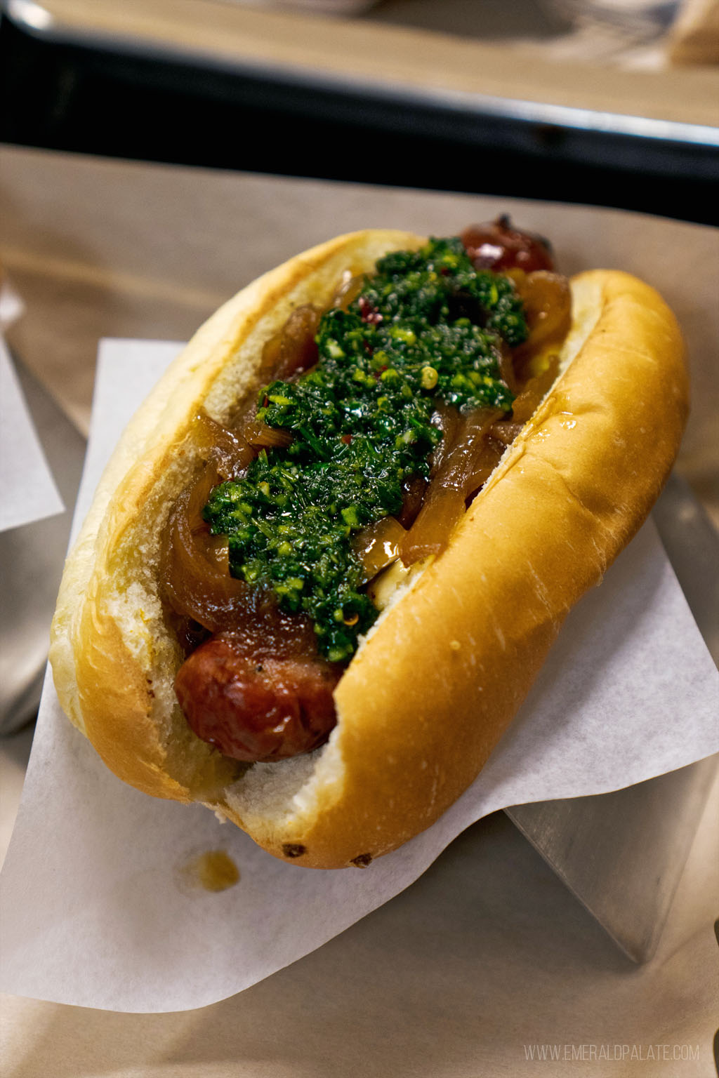 sausage in a bun topped with chimichurri