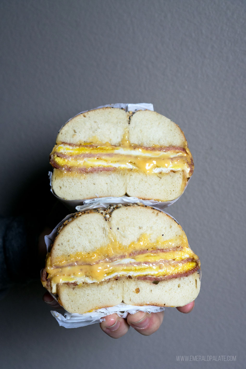 two halves of a bagel taylor ham, egg, and cheese sandwich stacked on top of each other