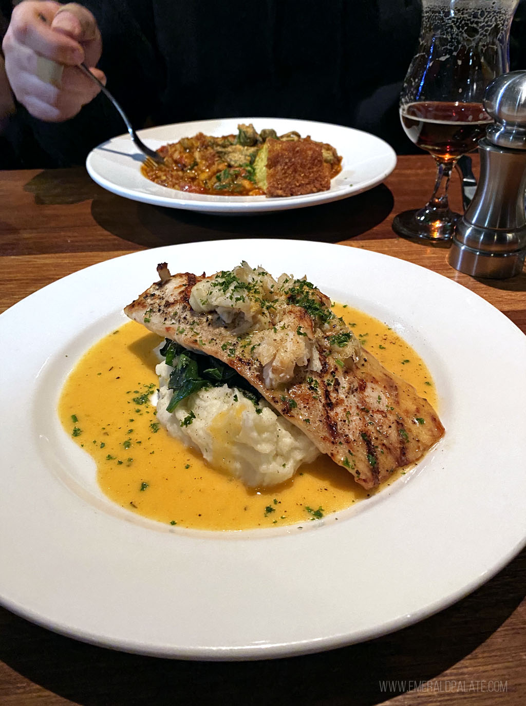 red fish over mashed potatoes with jambalaya in the background