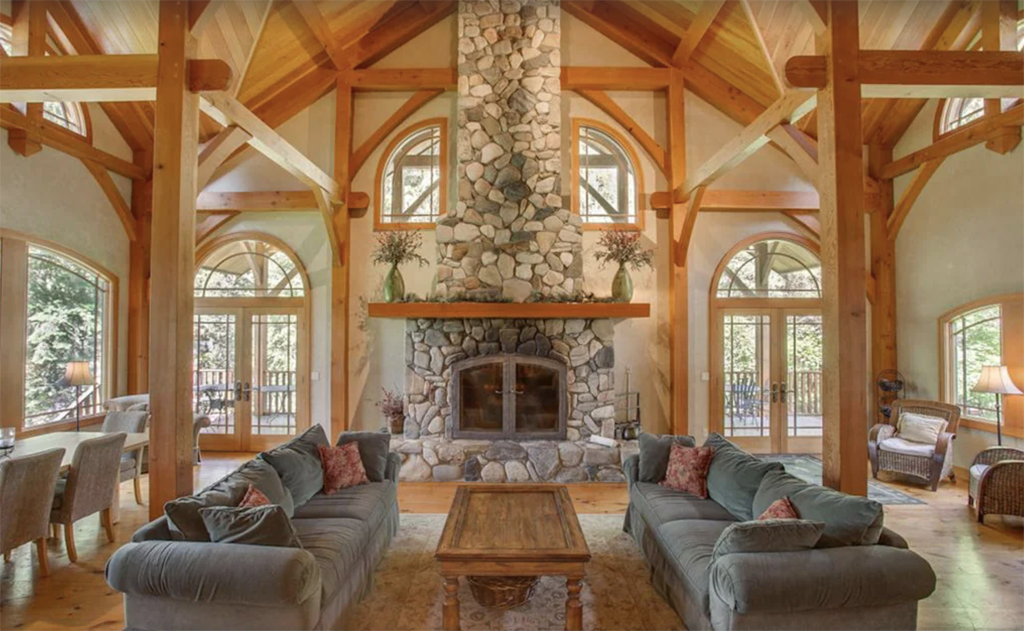 living room with a bunch of wood beams, a cathedral ceiling, and floor-to-ceiling stone fireplace