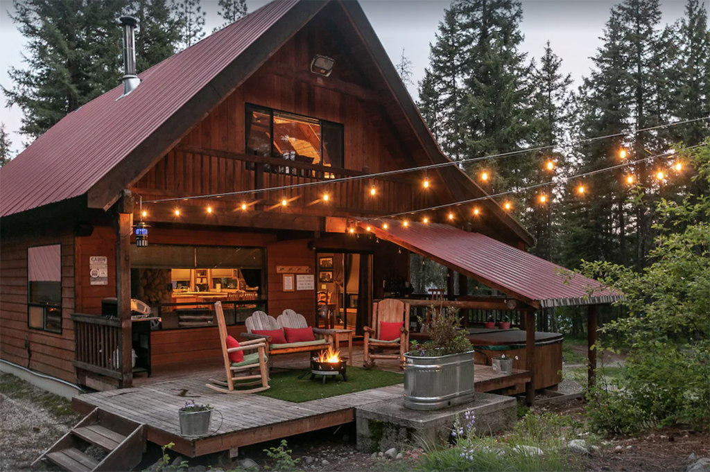 exterior of one of the best Leavenworth cabins with string lights, fire pit, and a hot tub