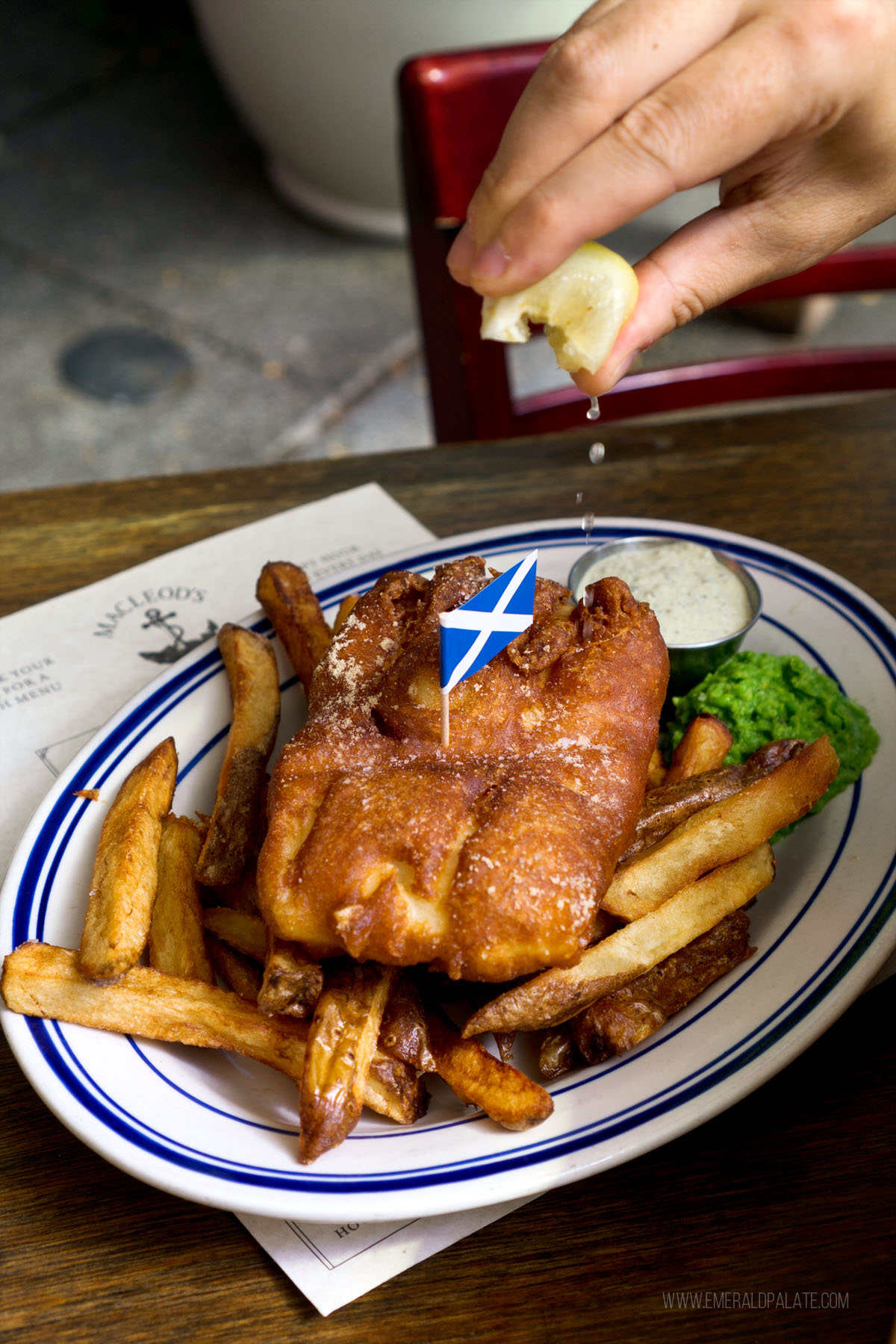 person squeezing lemon over some of the best fish and chips in Seattle