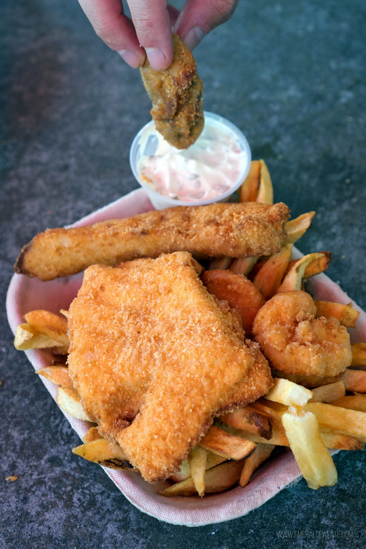 person dipping a fried oyster into tartare sauce at one of Seattle's best fish and chips spots