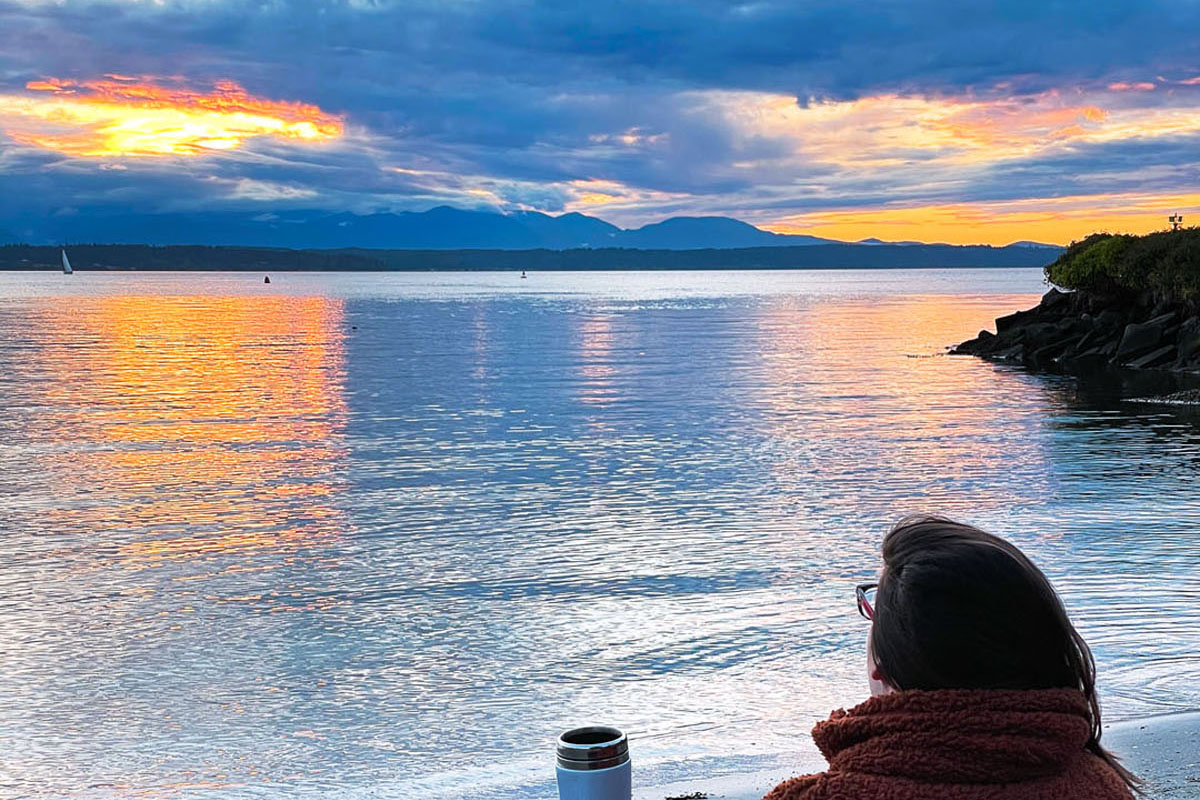 woman enjoying sunset on a beach that's one of the best hidden gems in Seattle