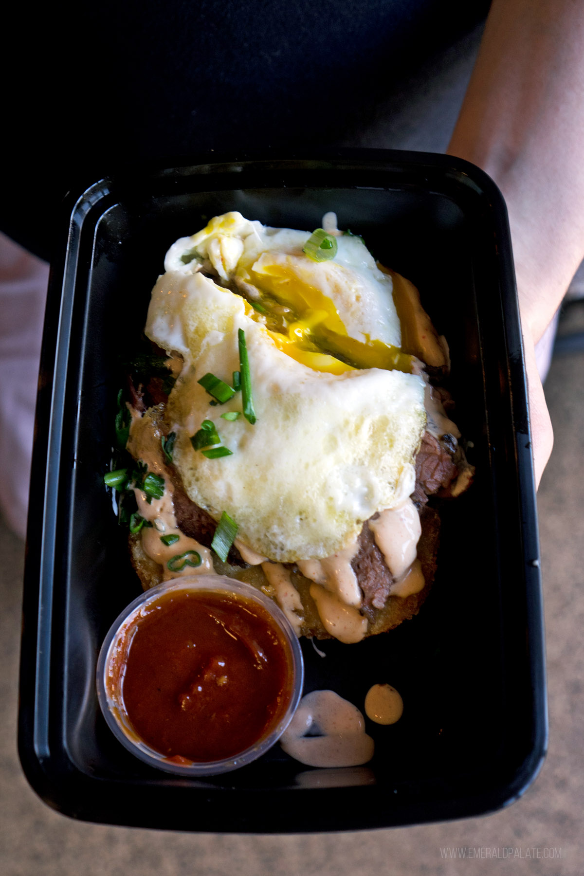 brisket in a takeout container with an egg on top