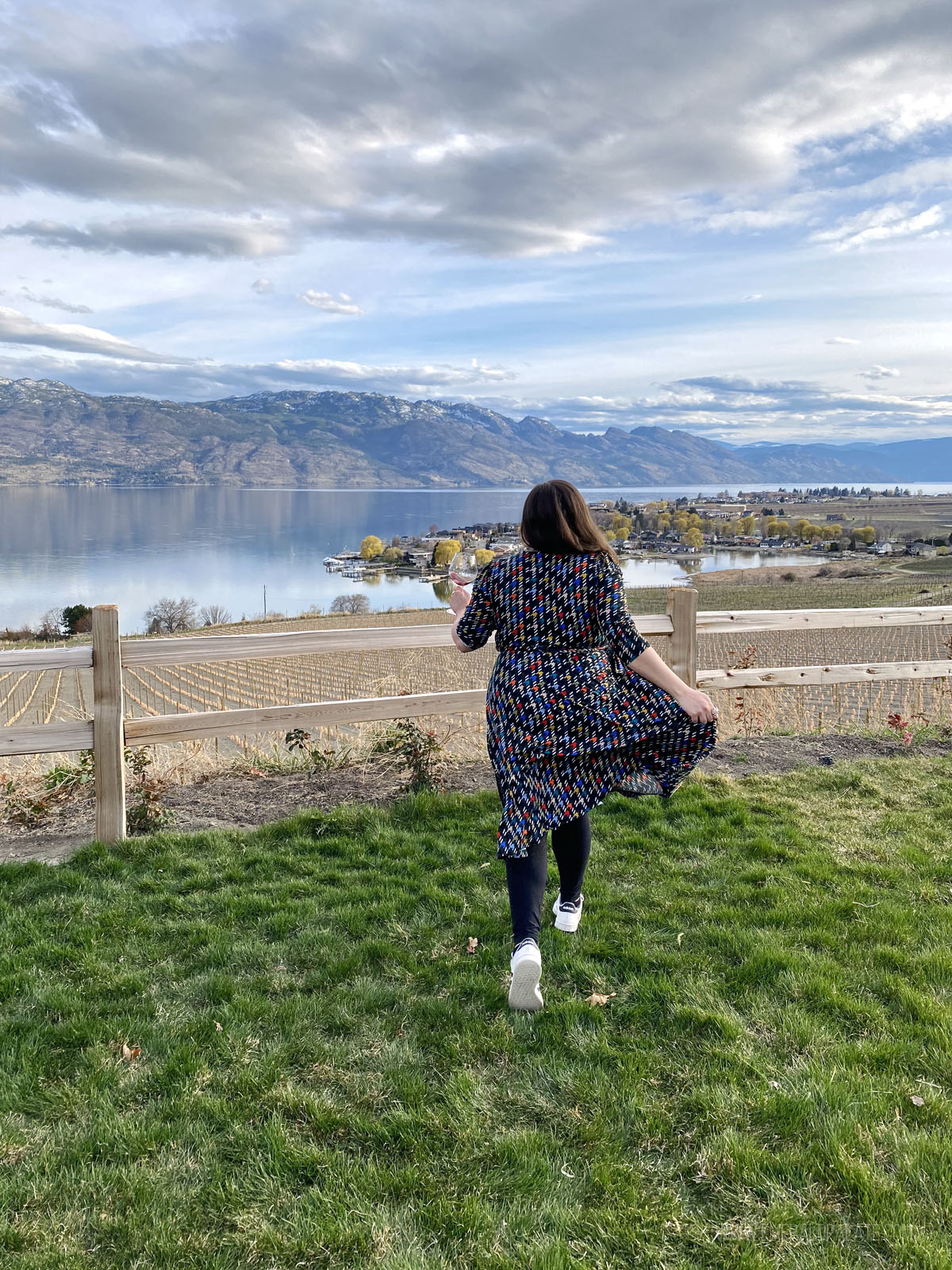 woman running at a winery with Okanagan Lake in the distance