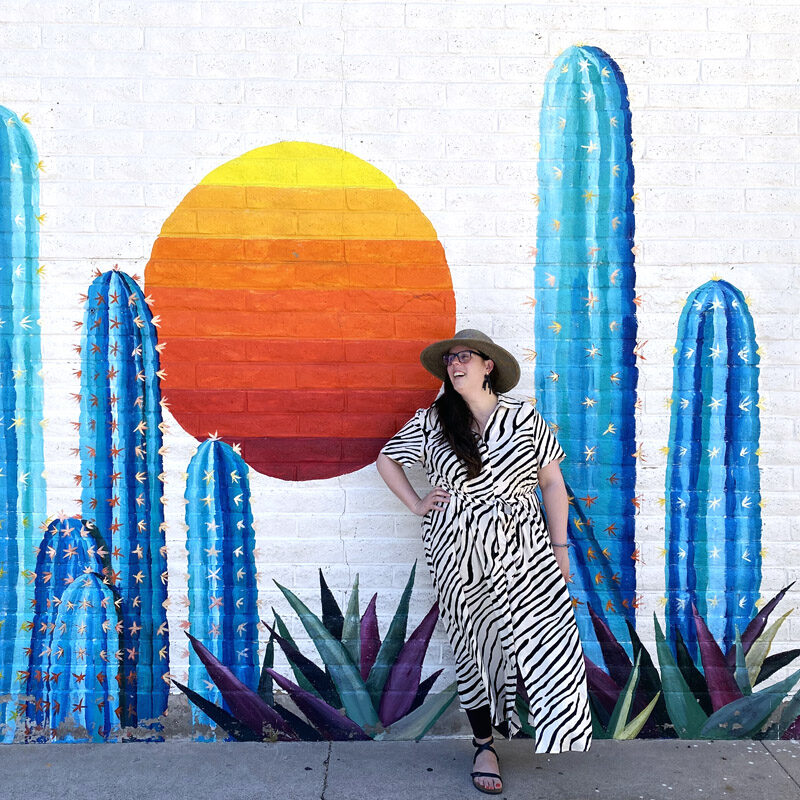 woman laughing in front of a cactus mural during her weekend in Scottsdale