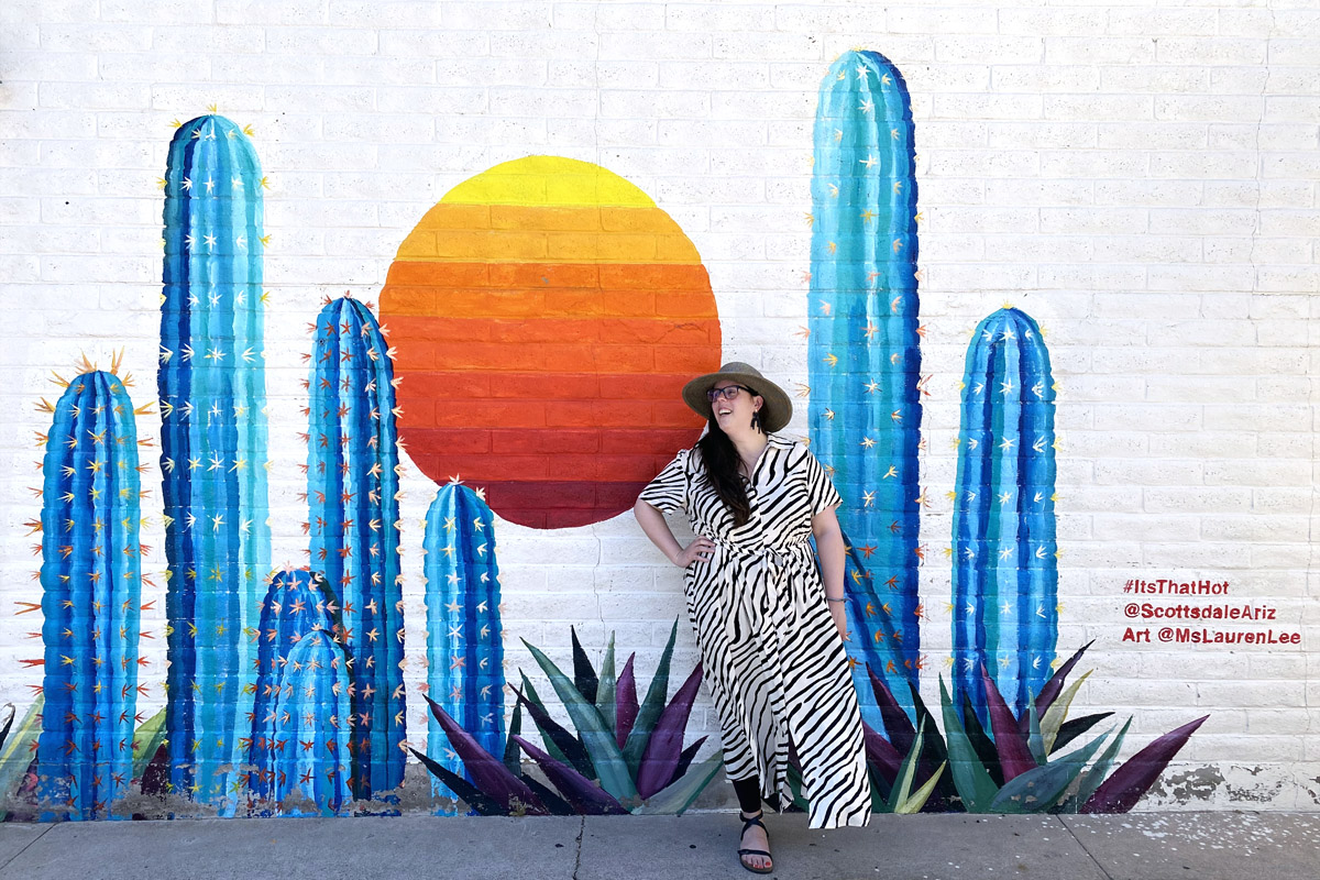 woman laughing in front of a cactus mural during her weekend in Scottsdale