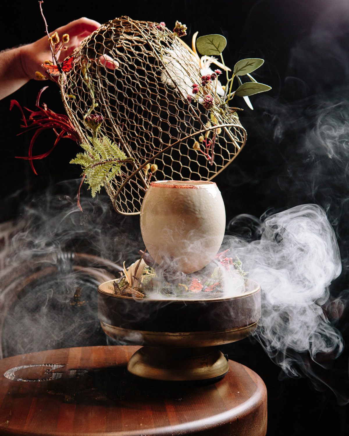 smoking cocktail inside an ostrich egg with a bird cage being lift off it
