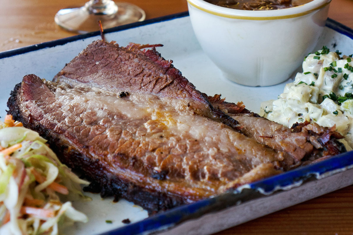 smoked brisket meat on a platter with sides at one of the best BBQ in Seattle restaurants