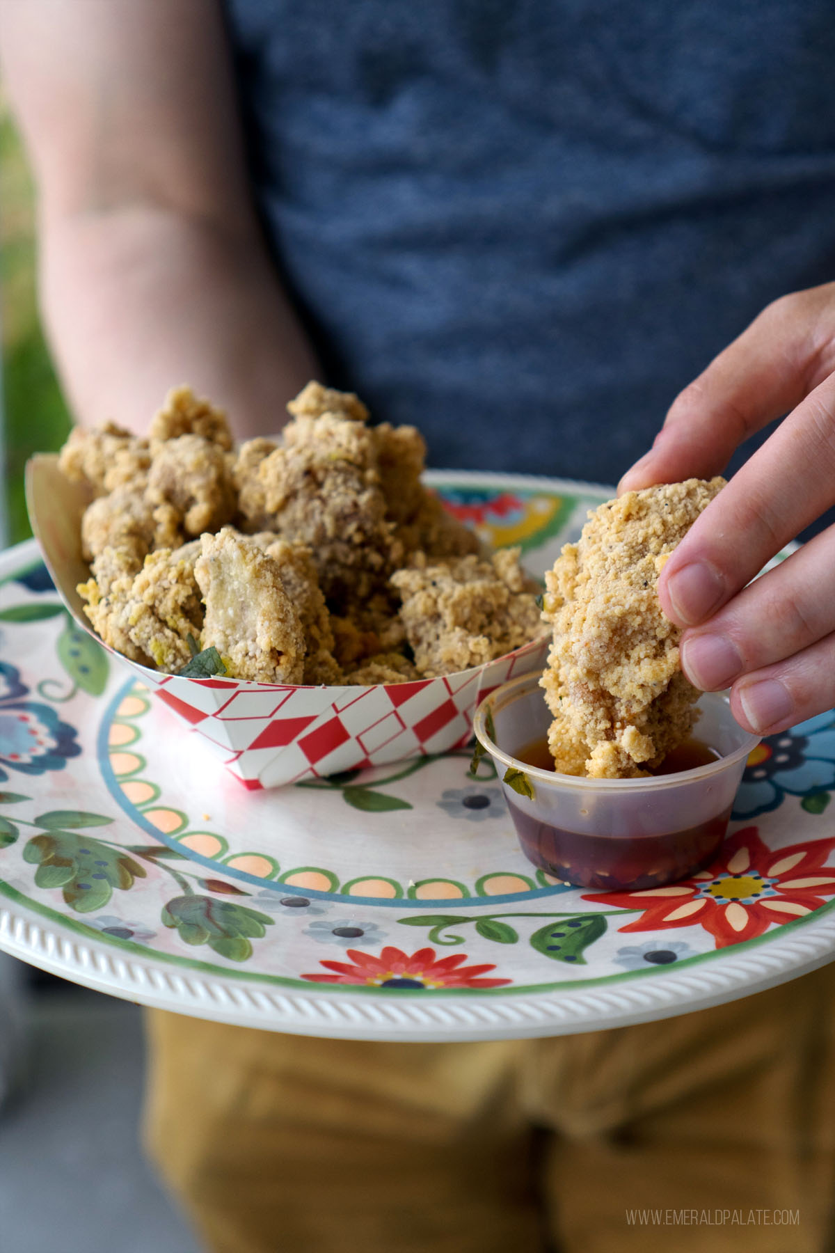 person dunking fried chicken into sauce