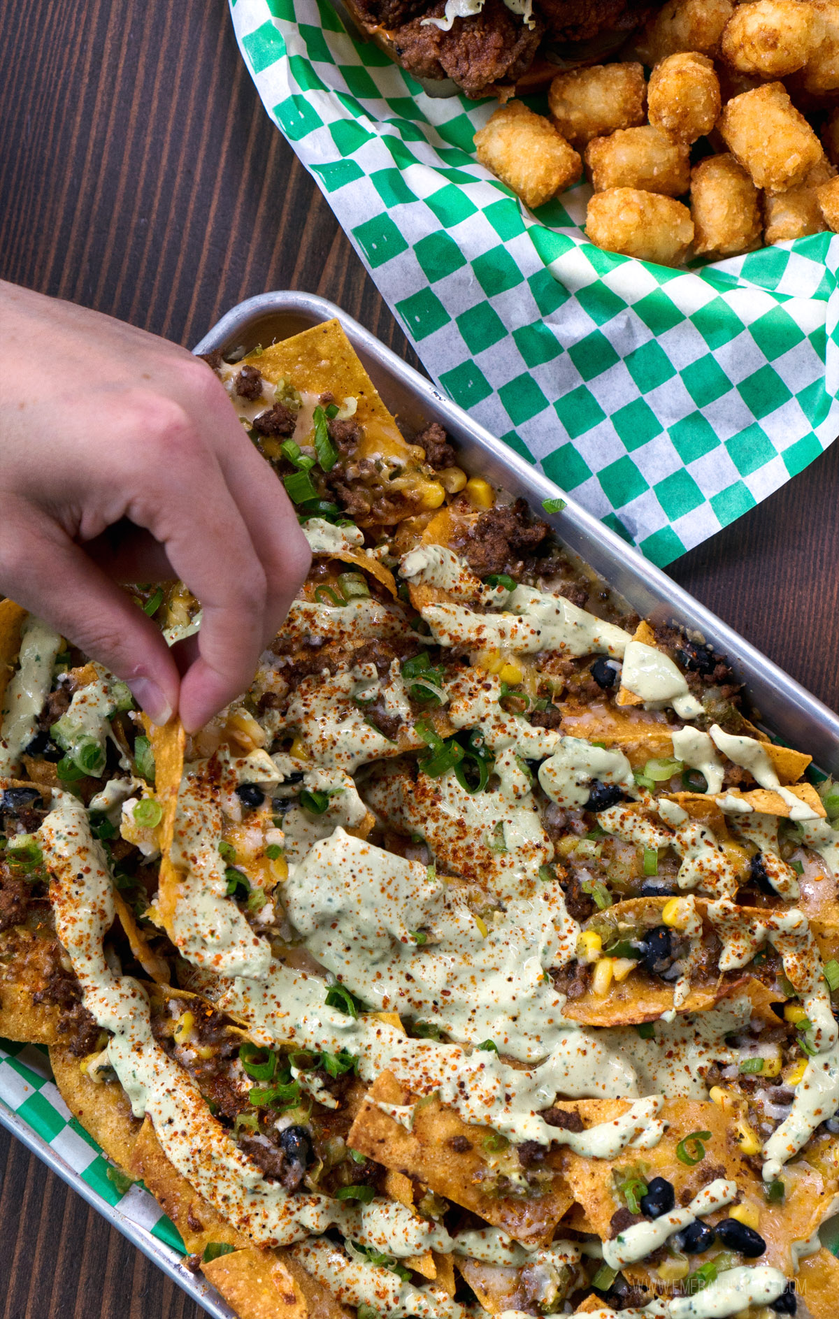 baking sheet with nachos covered in green crema sauce