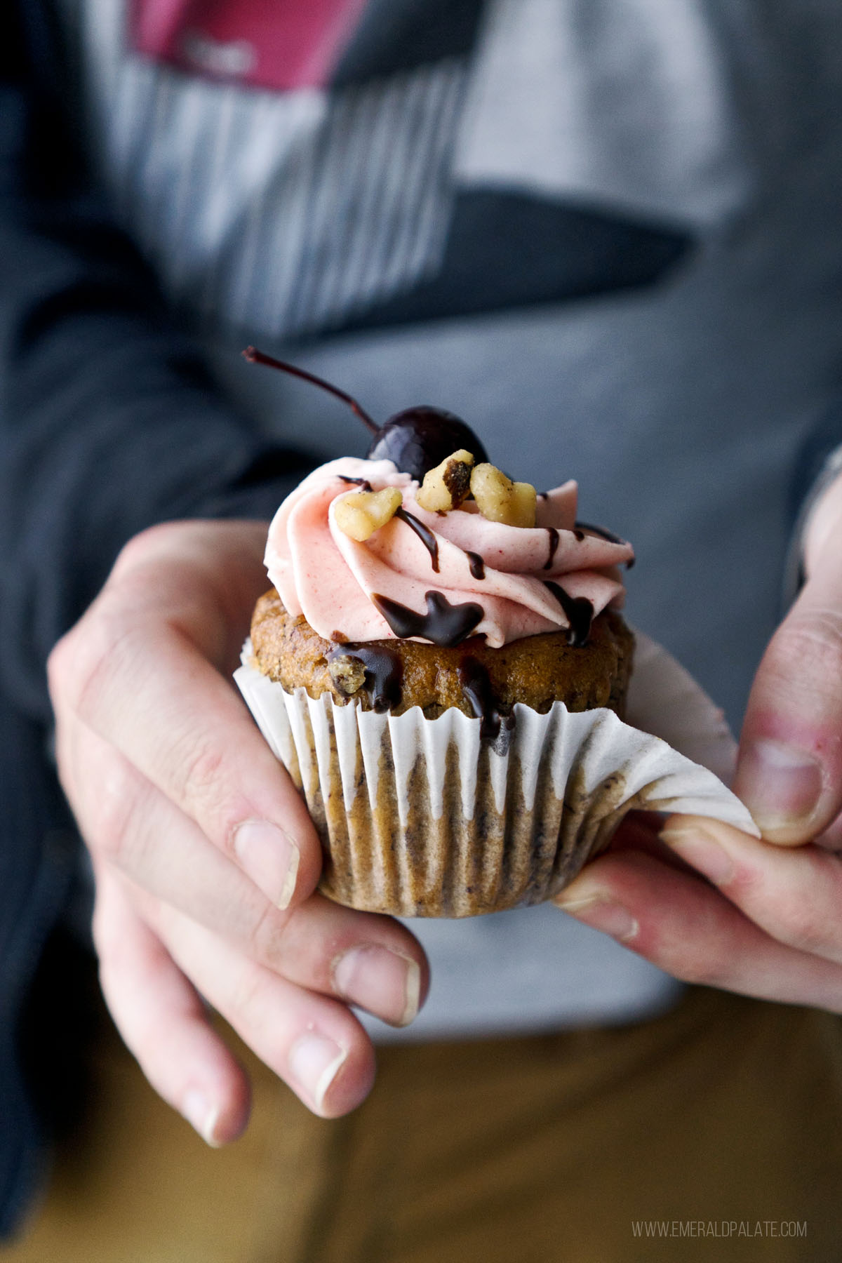 person peeling back paper from a cupcake