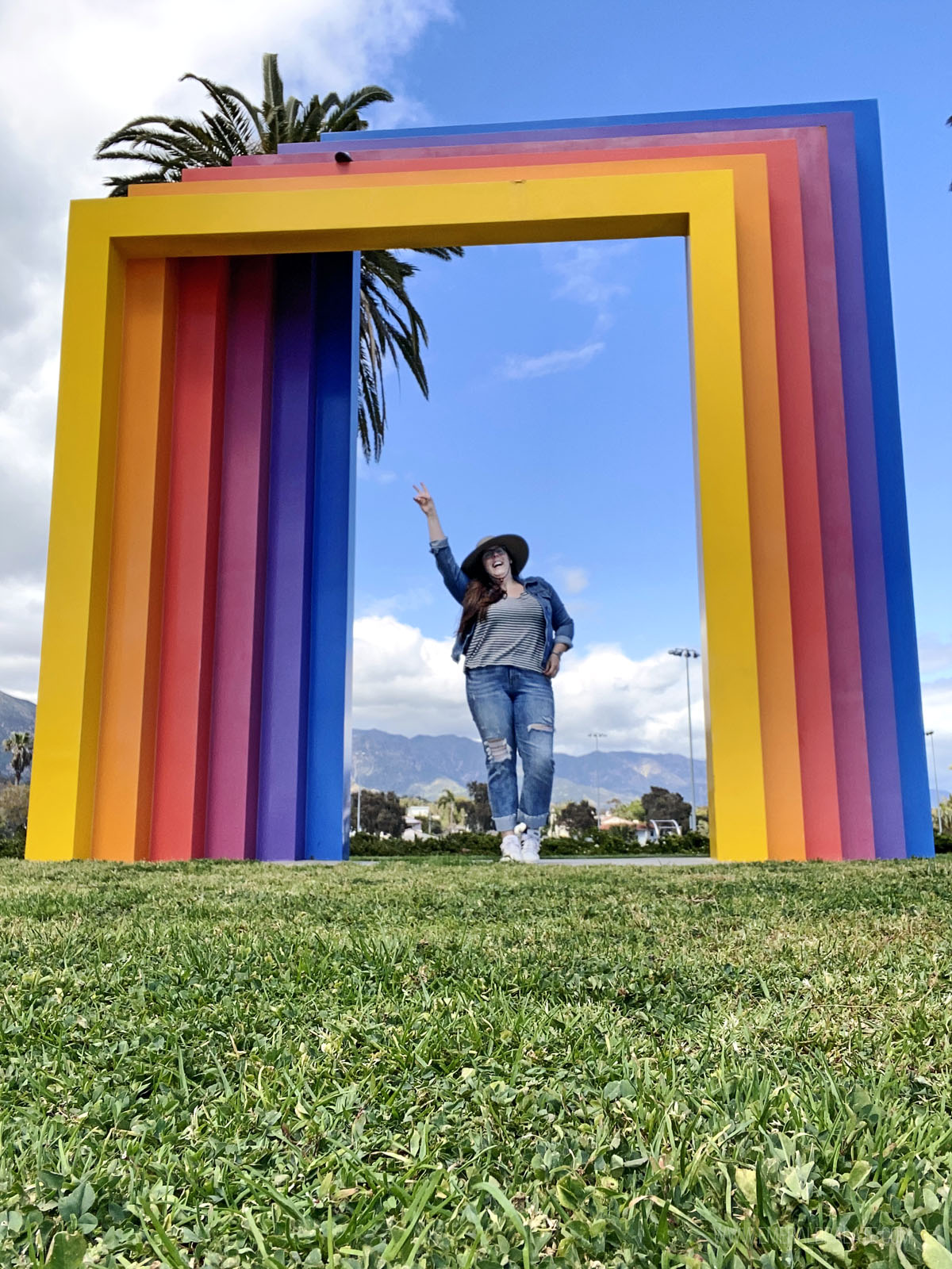 woman laughing with a peace sign under the Chromatic Gate in Santa Barbara