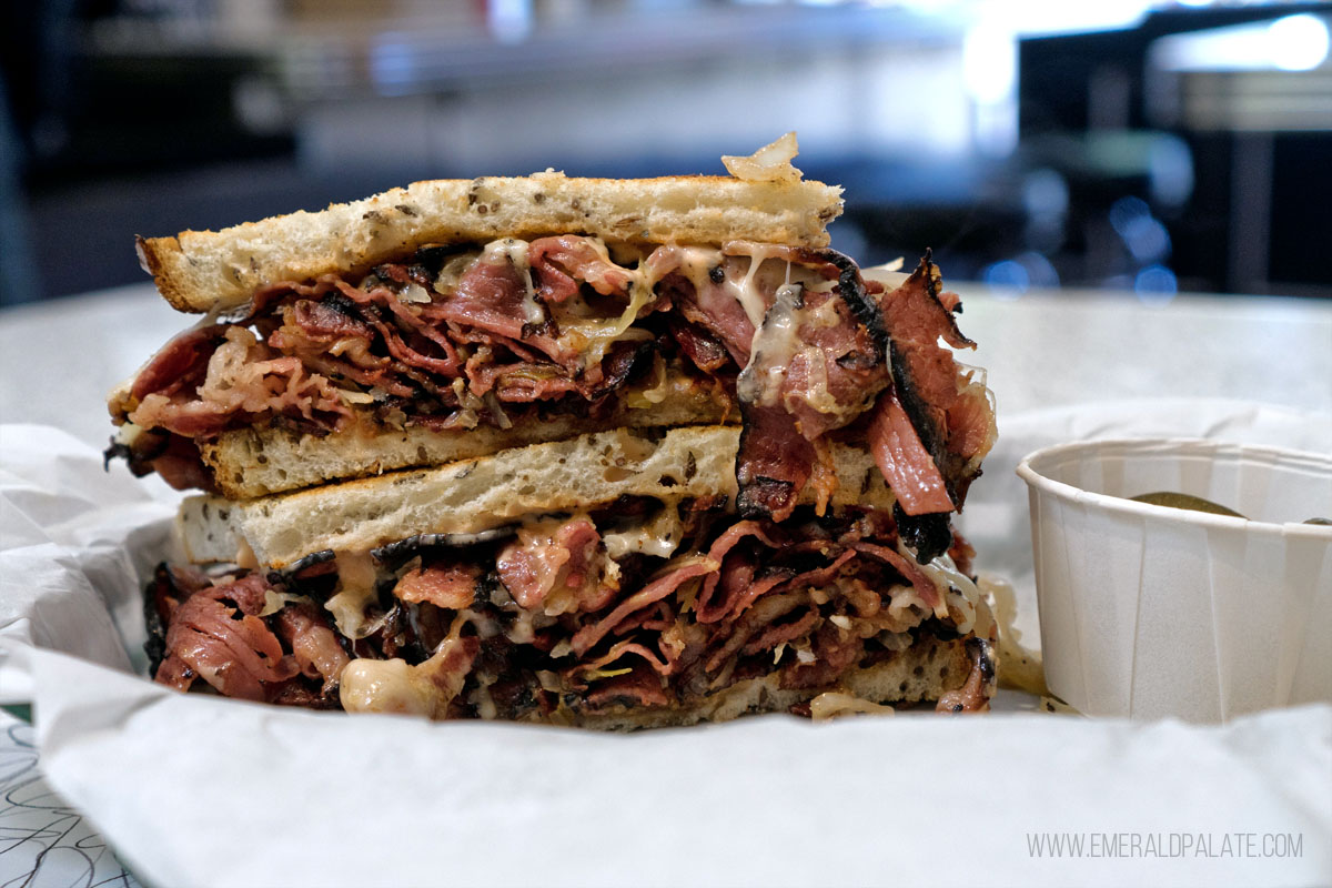 two halves of a pastrami sandwich stacked on top of each other