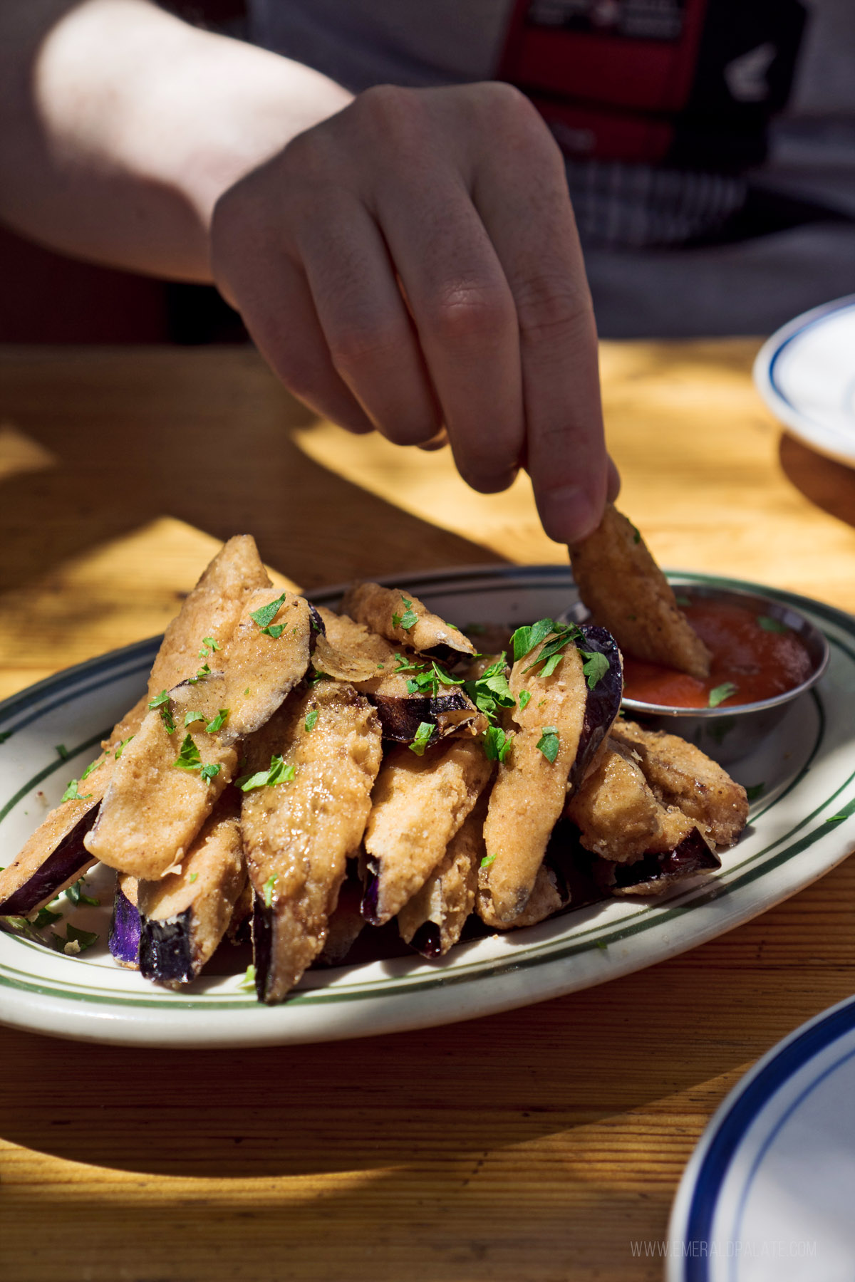 person dipping an eggplant fry into dip