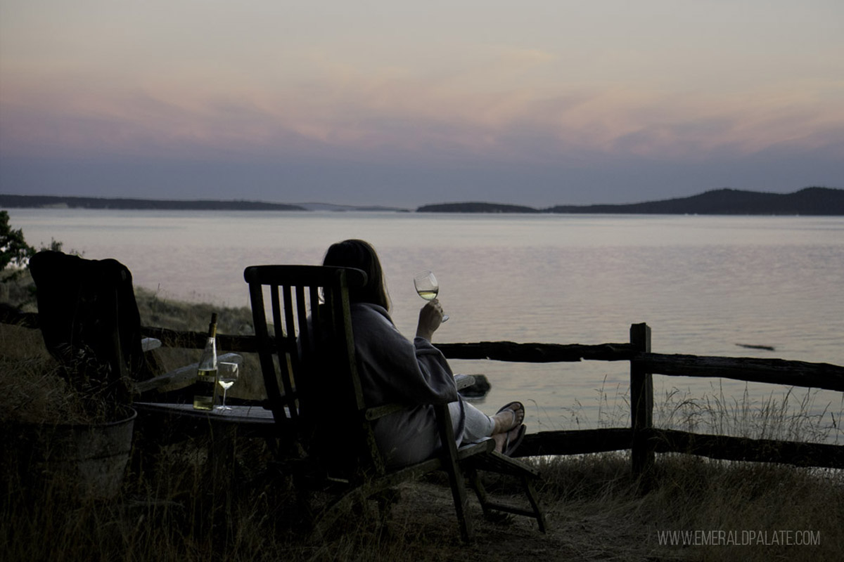 woman enjoying sunset over water with wine a one of the best Pacific Northwest cabins