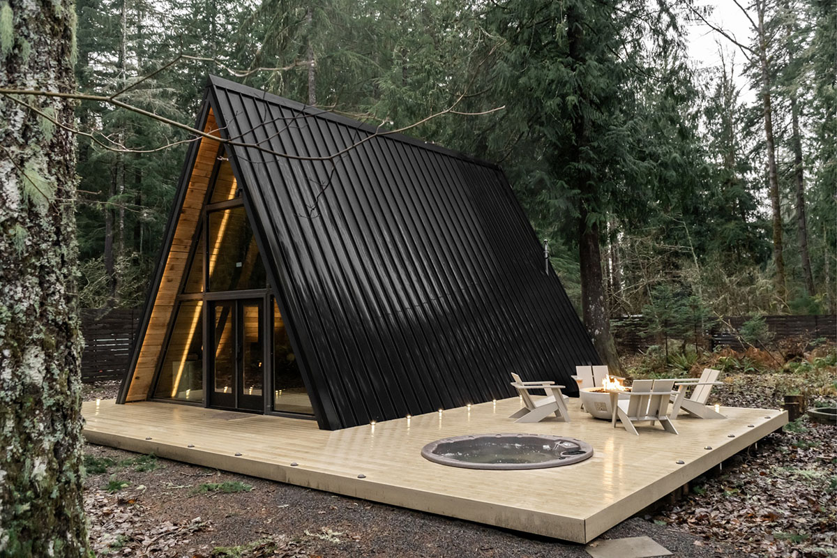 Modern a-frame cabin with a metal roof and deck with a hot tub built into it