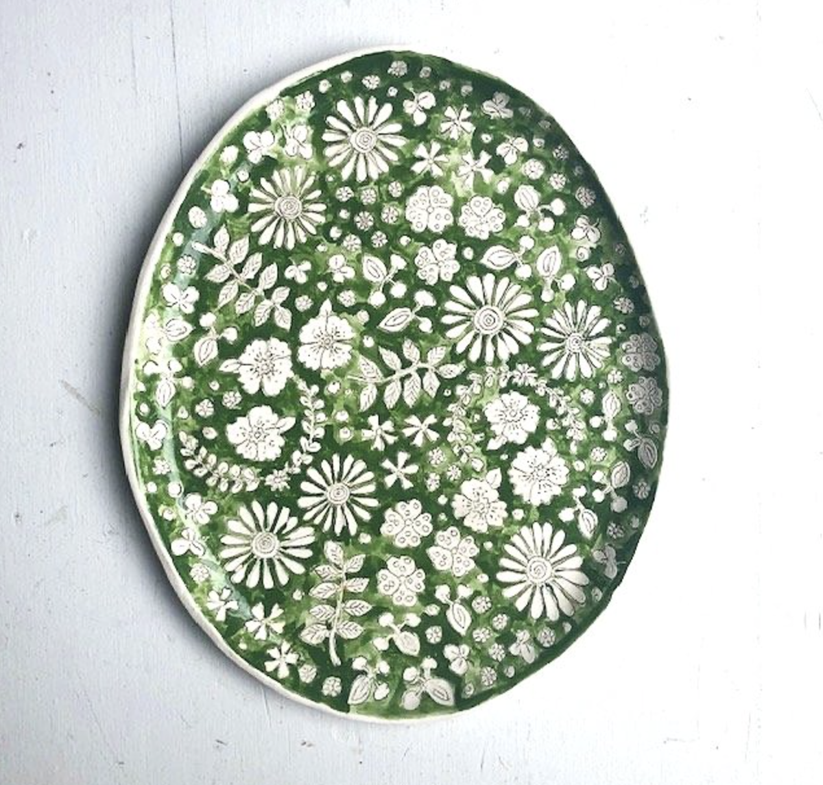 green platter engraved with intricate flower details, one of the best Seattle ceramics
