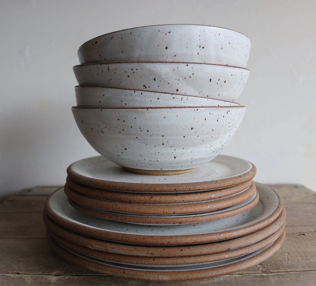 Stack of white speckled bowls and plates