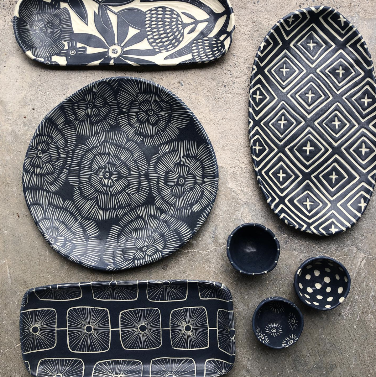 a bunch of ceramic plates and platters etched with floral and geo pattens