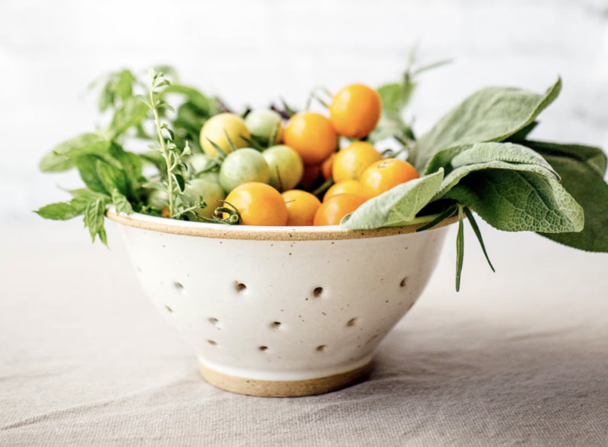 ceramic sieve with fruit and herbs coming out of it