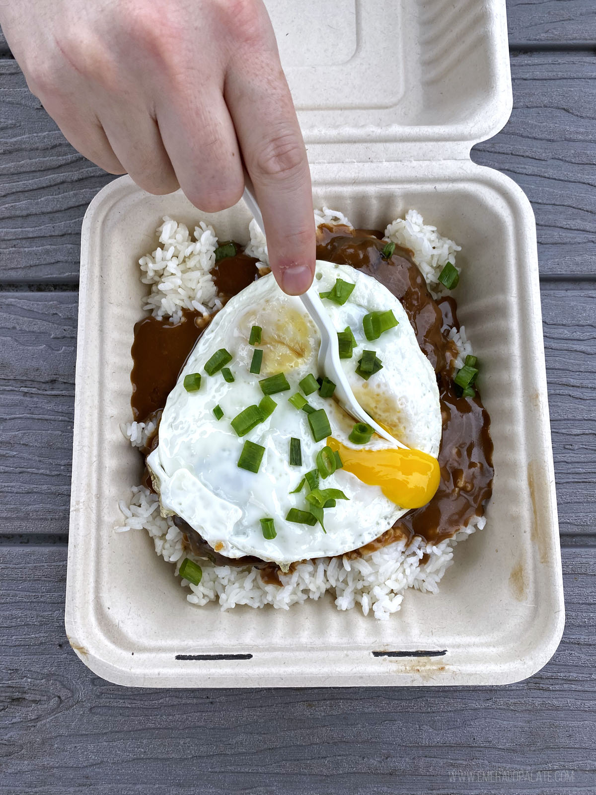 person cutting an egg in loco moco in Maui