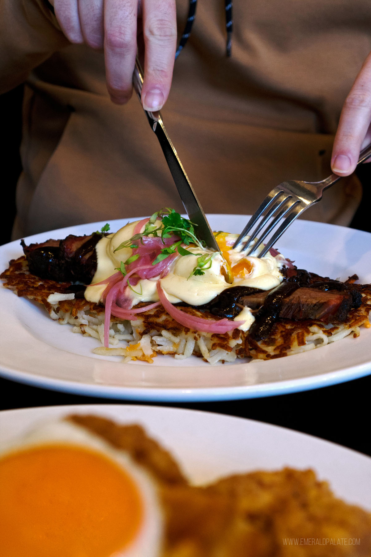 person cutting into a poached egg from a brunch spot in Victoria BC