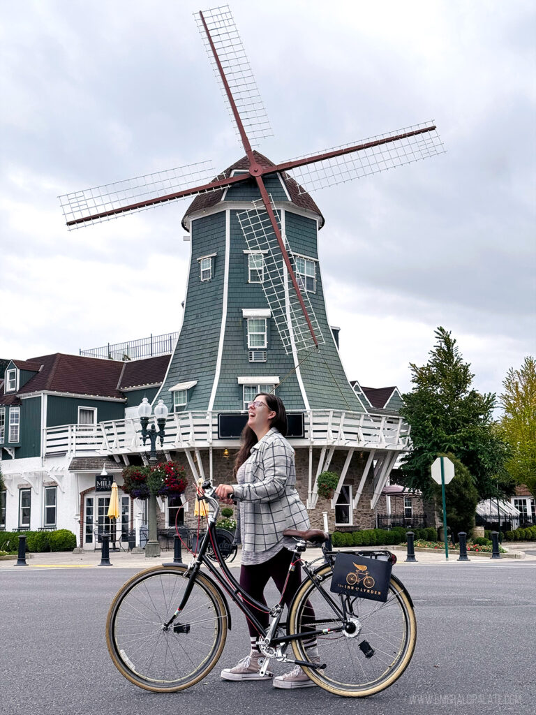 woman riding a vintage bike and posing in front of a windmill in one of the cutest small towns in Washington state