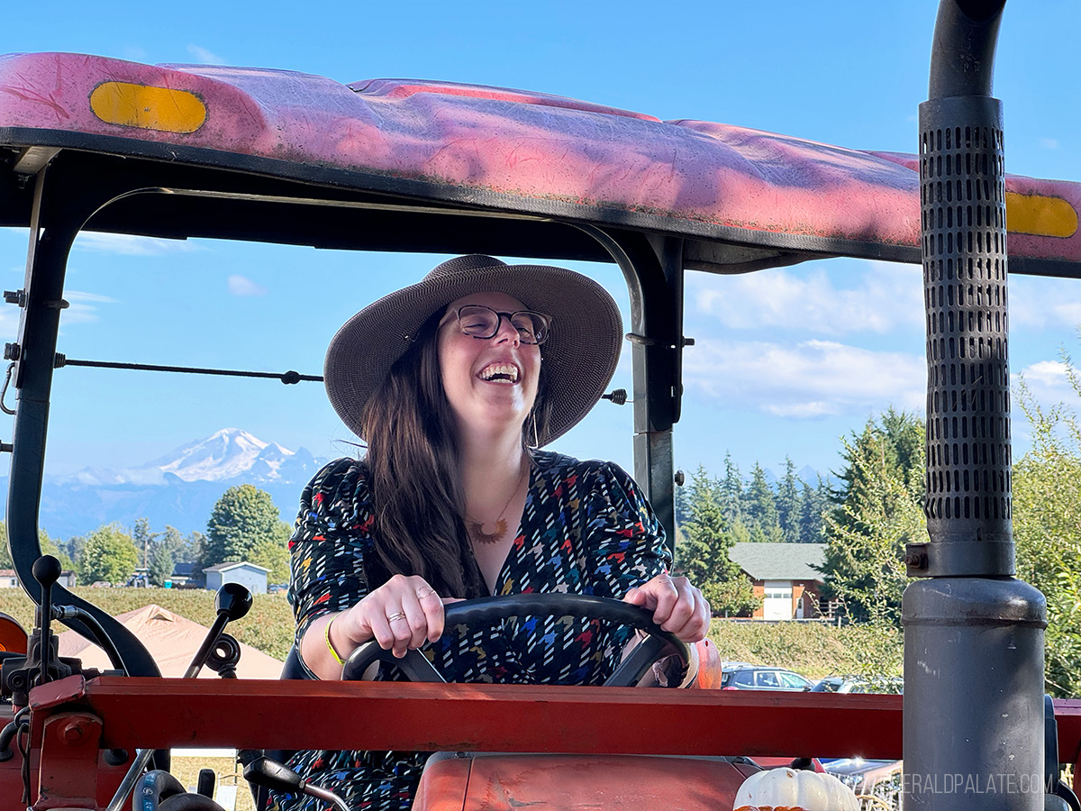 woman laughing on a tractor with Mt Baker in the background