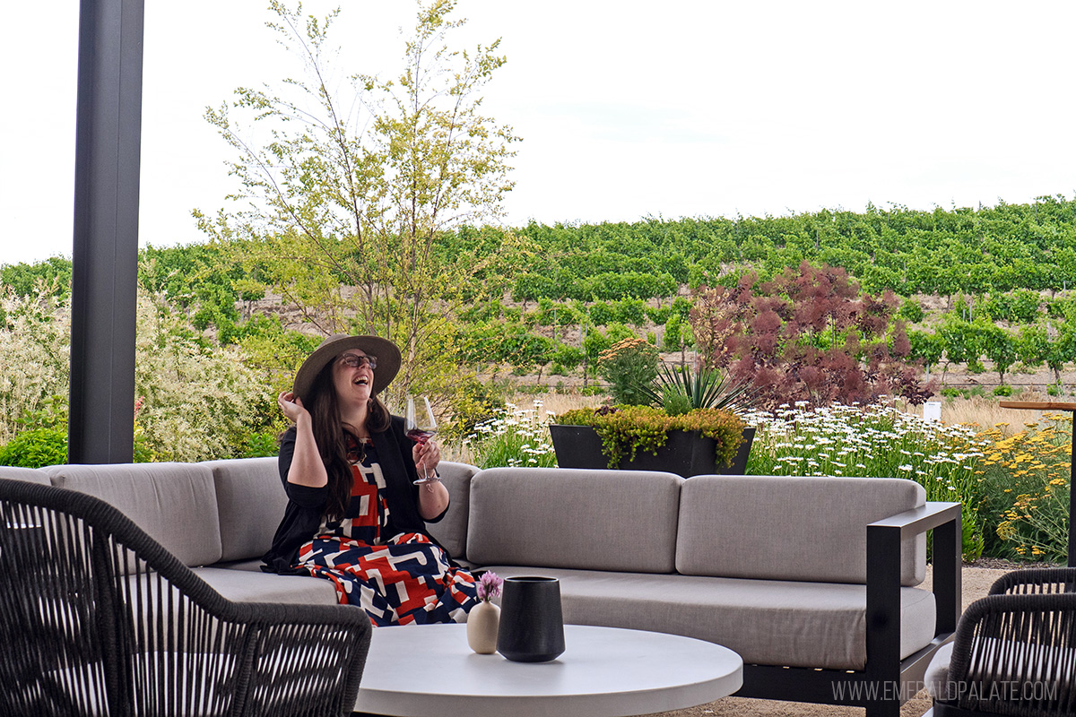woman laughing on an outdoor couch while sipping wine