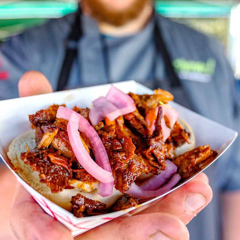person handing out a BBQ food sample at one of the best festivals in Washington State