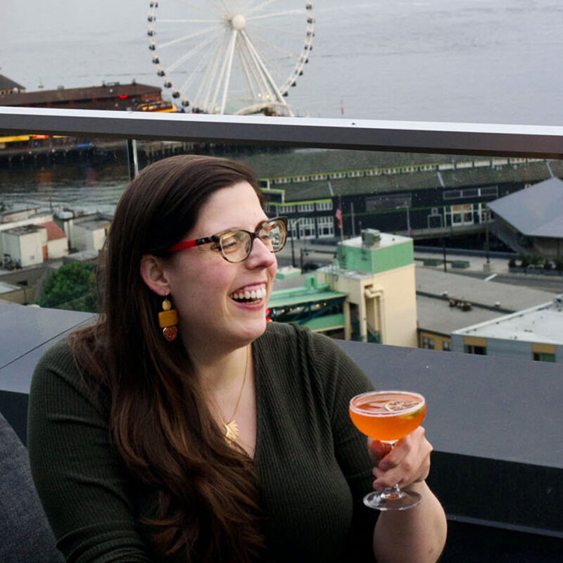 woman drinking a cocktail on a rooftop bar, one of the best bachelorette party ideas in Seattle