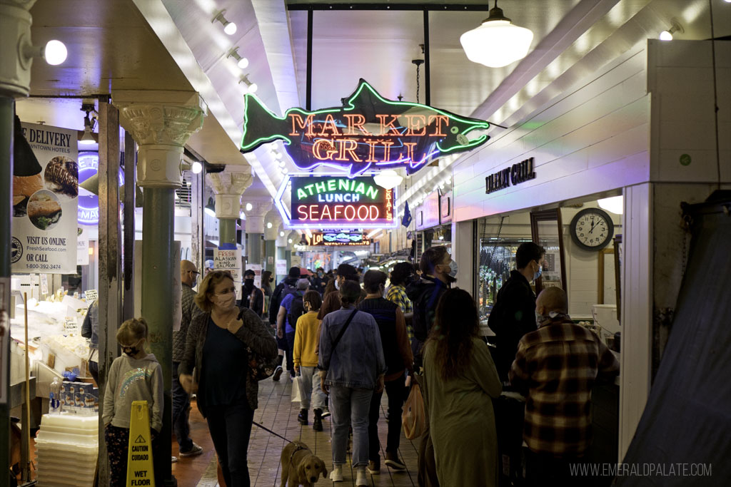 people walking among the neon signs at Pike Place Market