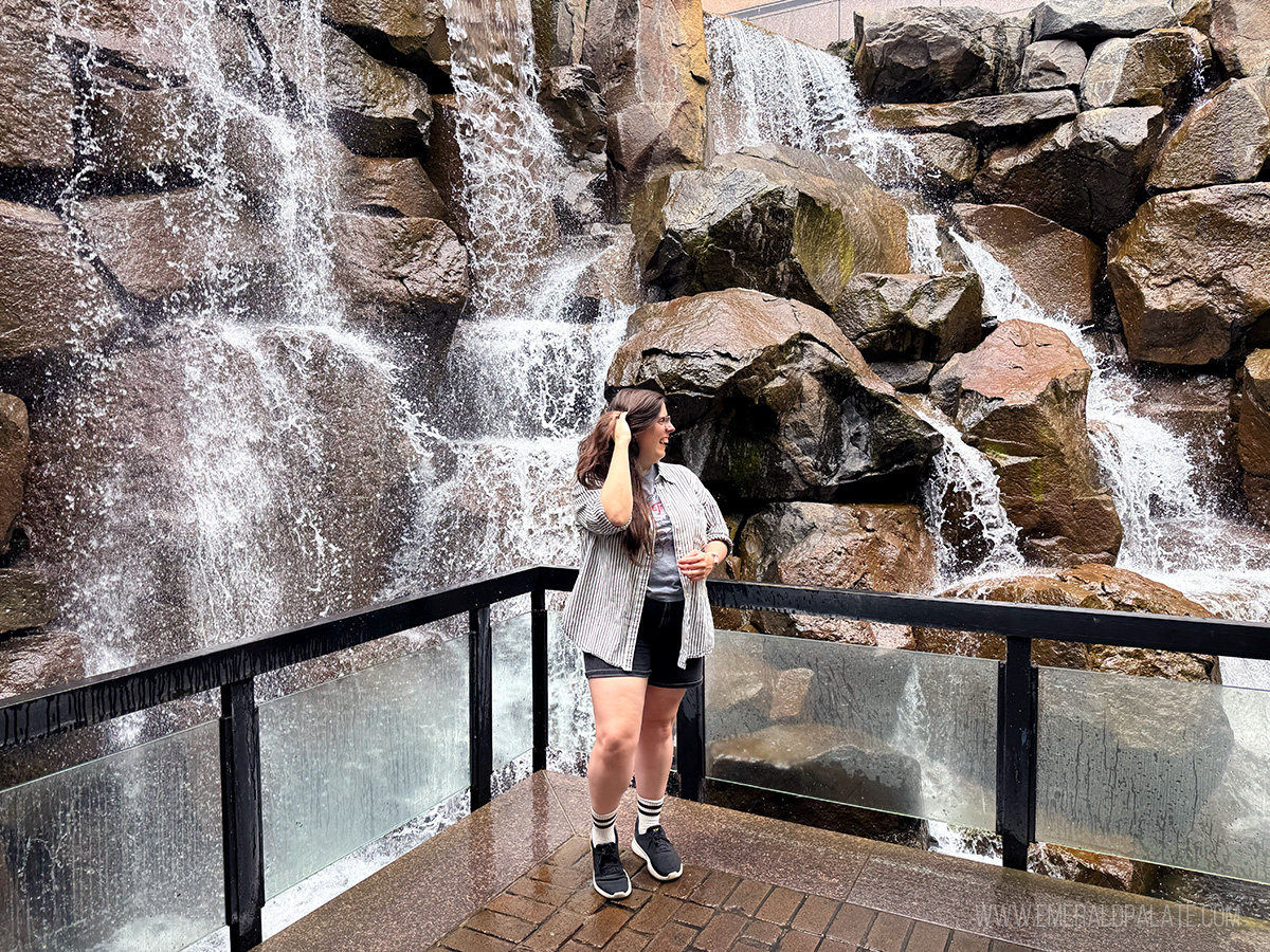 woman laughing in front of a waterfall, one of the Instagrammable places in Seattle