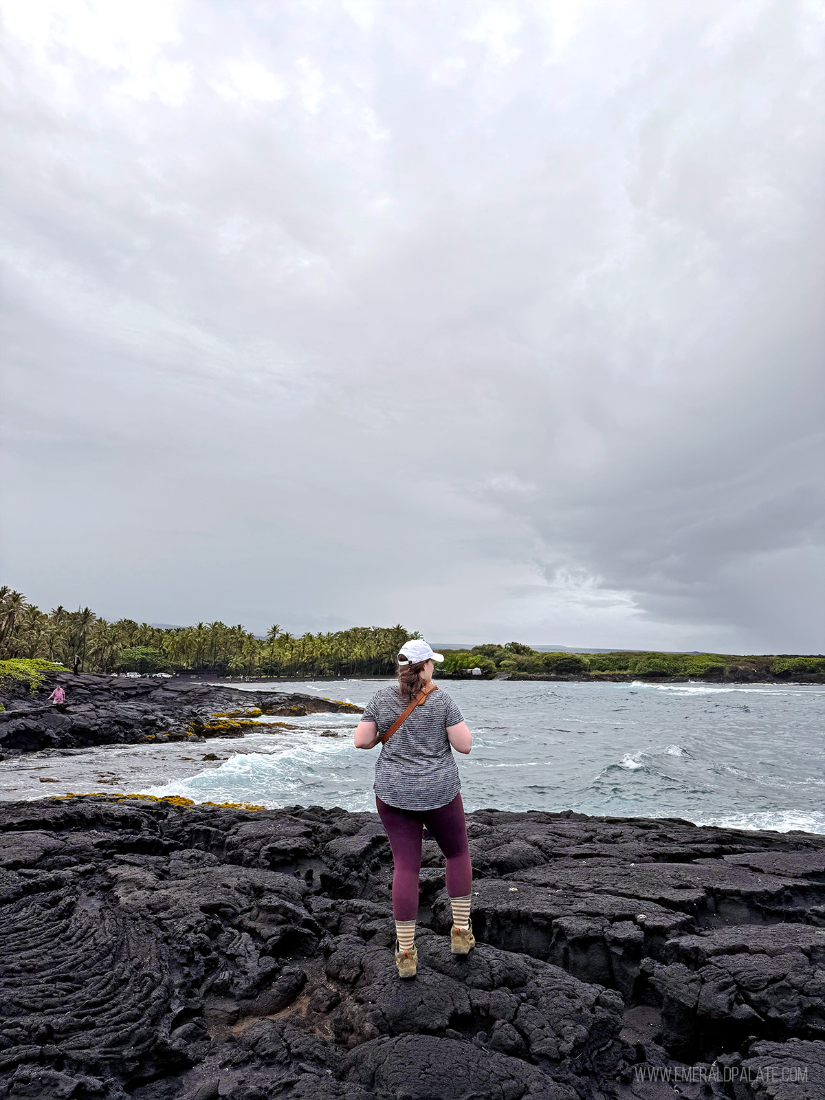 woman taking in the water views on a black sand beach in Hawaii