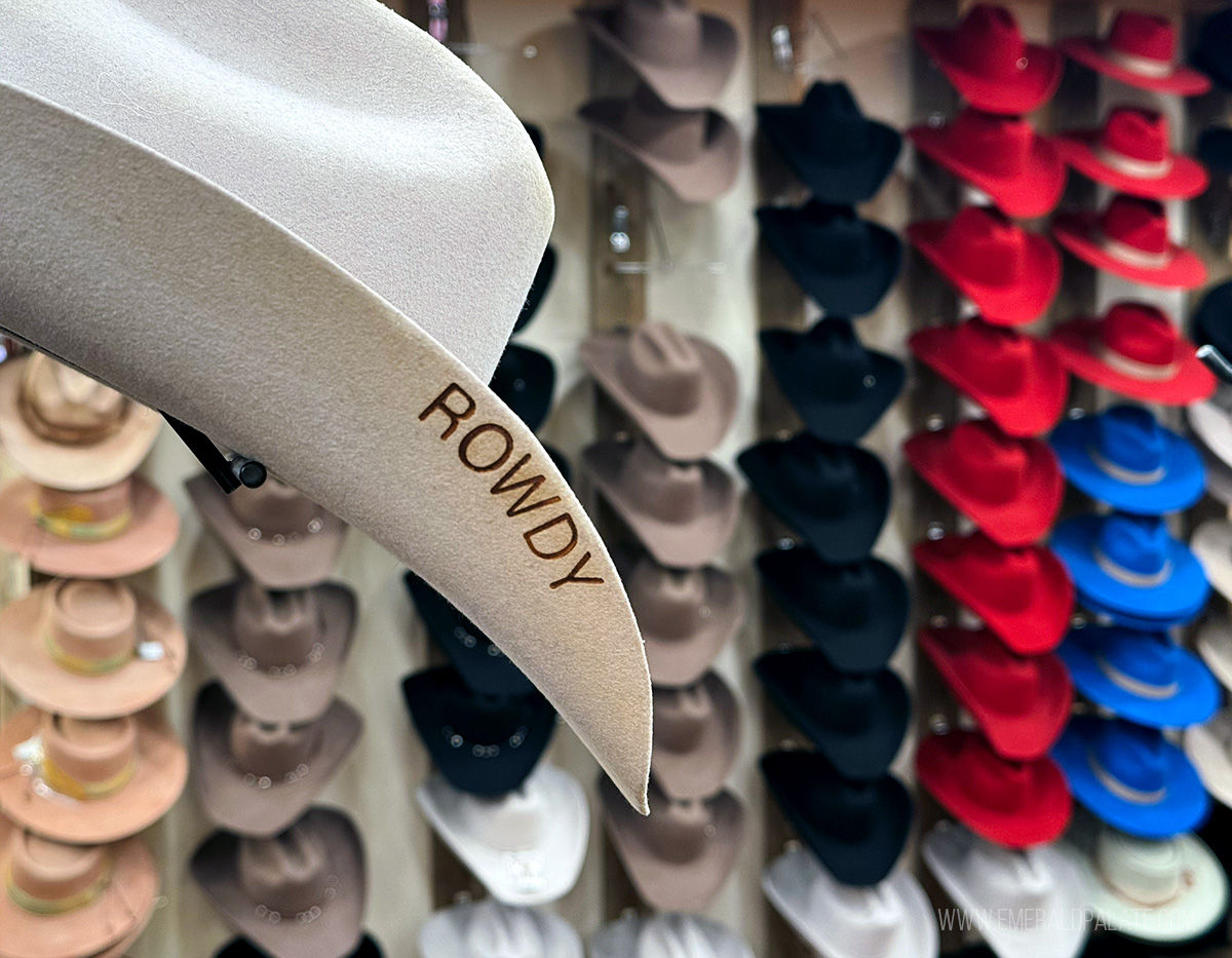 cowboy hat branded with the word "rowdy" and a hat wall behind it
