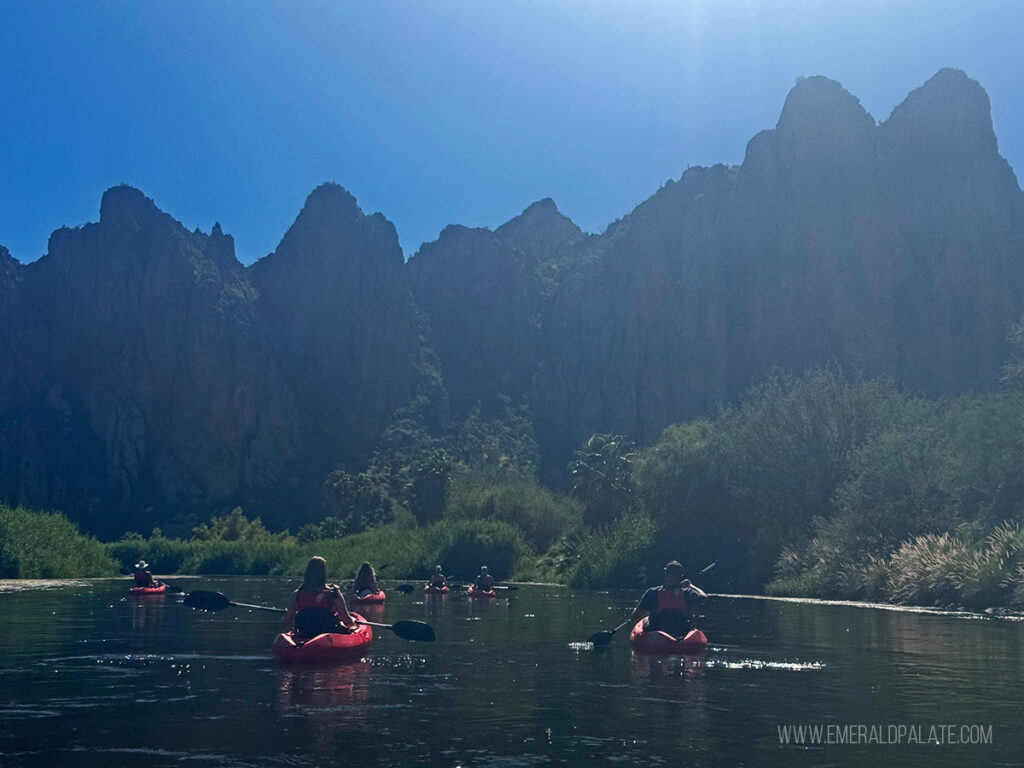 people kayaking on the Salt River with the mountains in the distance, one of the best things to do in Scottsdale, Arizona