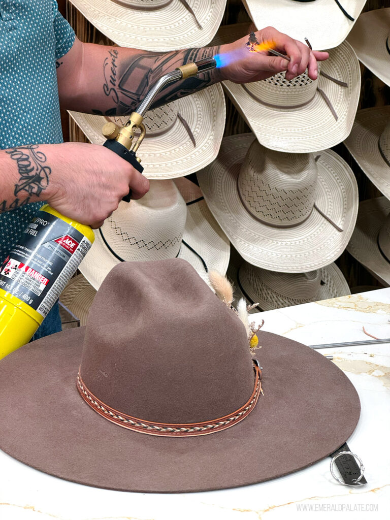 person firing up a branding iron while making a cowboy hat
