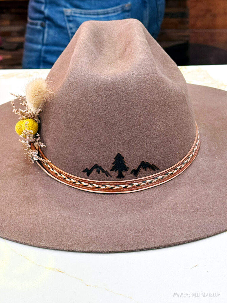 custom cowboy hat with 2 mountains and a pine tree branded in the back of it