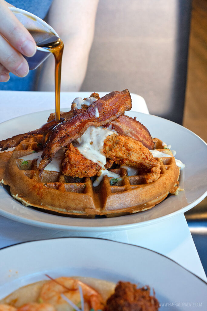 person pouring syrup over fried chicken and waffles at one of the most unique restaurants in Scottsdale