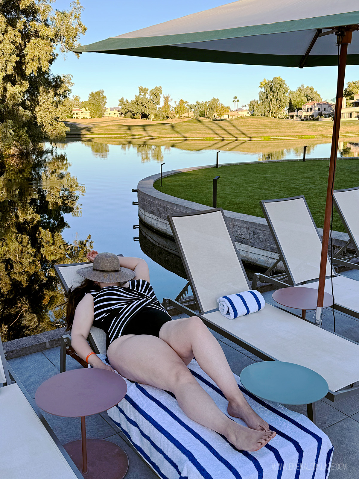woman lounging by the pool with a golf course and pond in the background