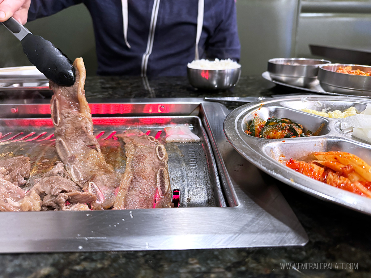 person picking up kalbi beef ribs from a KBBQ grill in Seattle
