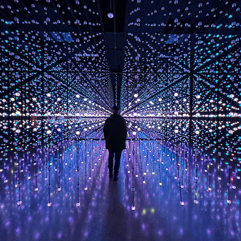 man walking through blinking light strands at an art museum one of the best things to do in Portland Oregon during winter